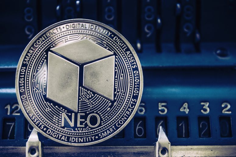 Coin cryptocurrency Neo on the background of numbers of the arithmometer. Concept mining or NEO course.