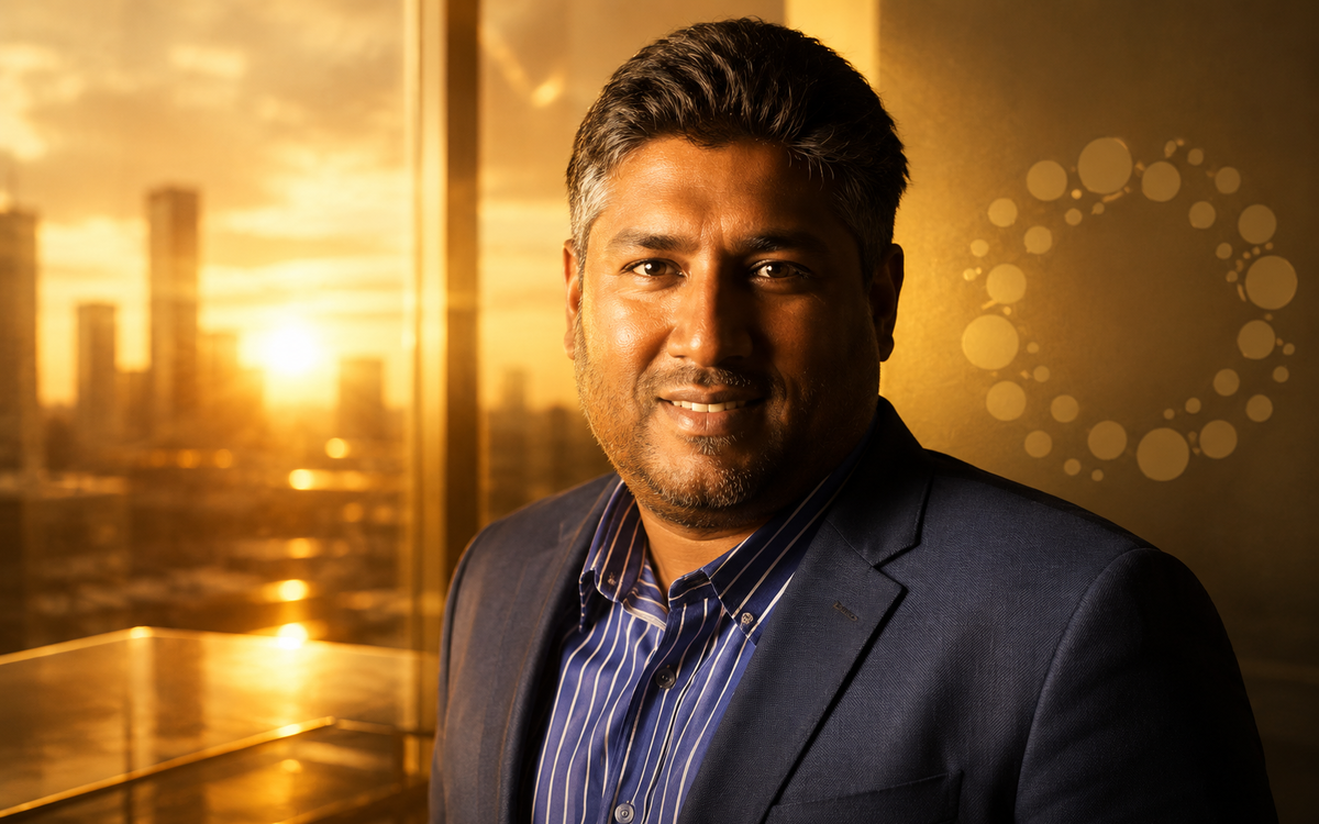 Vinny Lingham with a subtle Praxos Capital logo in a golden-hour office overlooking a modern city skyline.