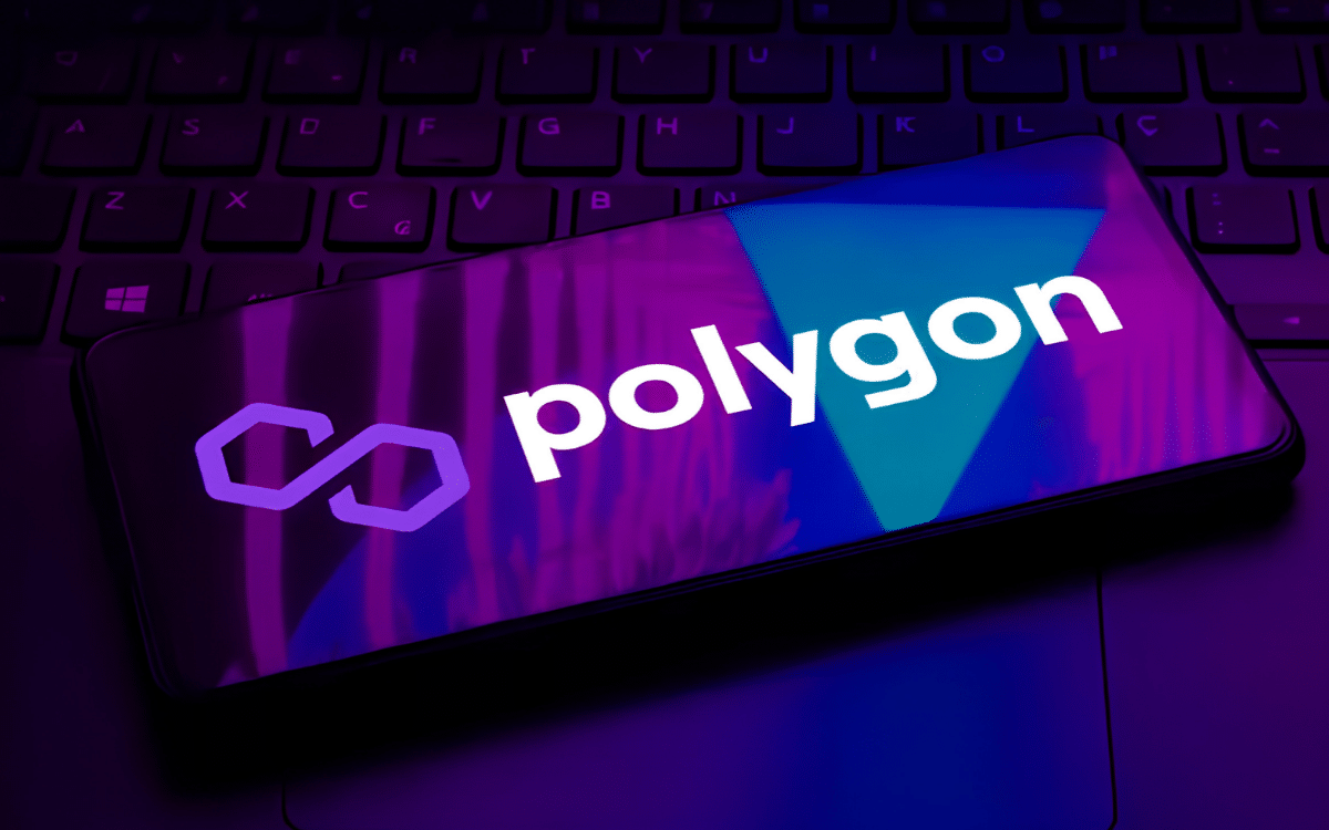 An image showing a Polygon logo on a phone placed on a keyboard with blue and purple illumination.